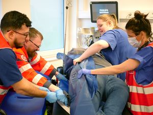 Mitarbeiter von Rettungsdienst und Klinik lagern gemeinsam eine Patientin um.